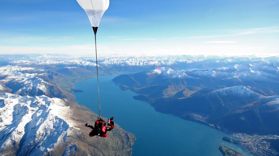 Parachute open above snow-capped mountains and Lake Wakatipu