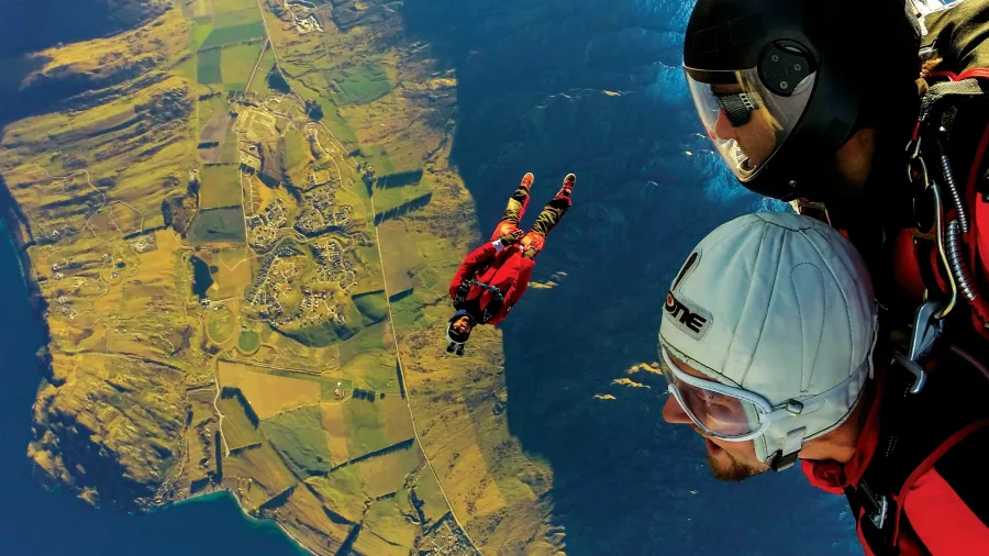 Pair of tandem skydivers over Queenstown farmland and lake views
