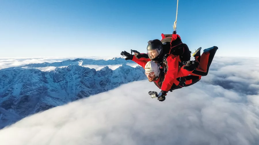 Tandem skydivers floating above the clouds near The Remarkables