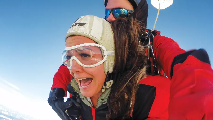 Close-up of tandem skydiver’s expression during freefall above Queenstown