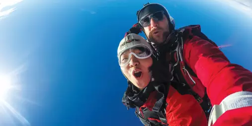 Tandem skydiving selfie with blue sky and wide-angle view above Queenstown