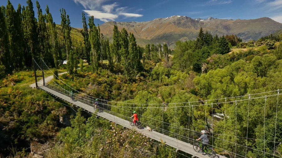 E-bike riders crossing a suspension bridge on the Otago trail