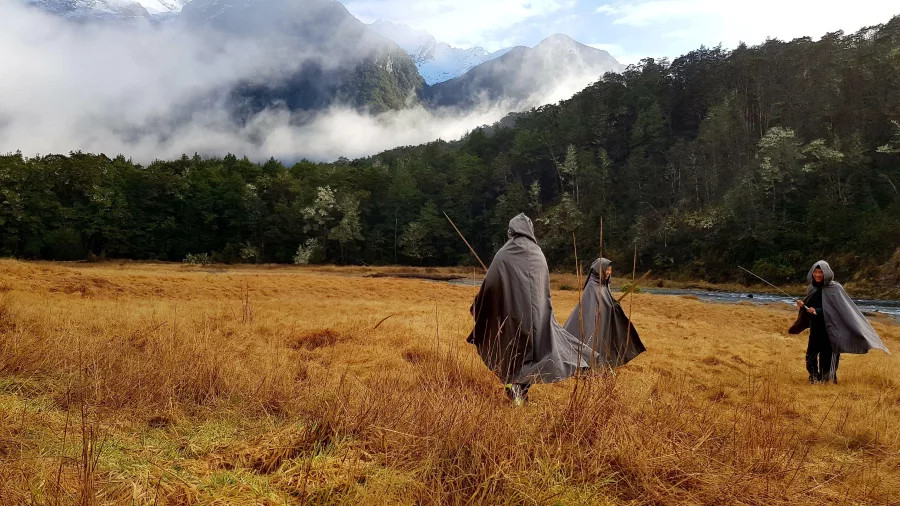 Tour group in cloaks recreating a scene from The Lord of the Rings in a grassy field near Queenstown