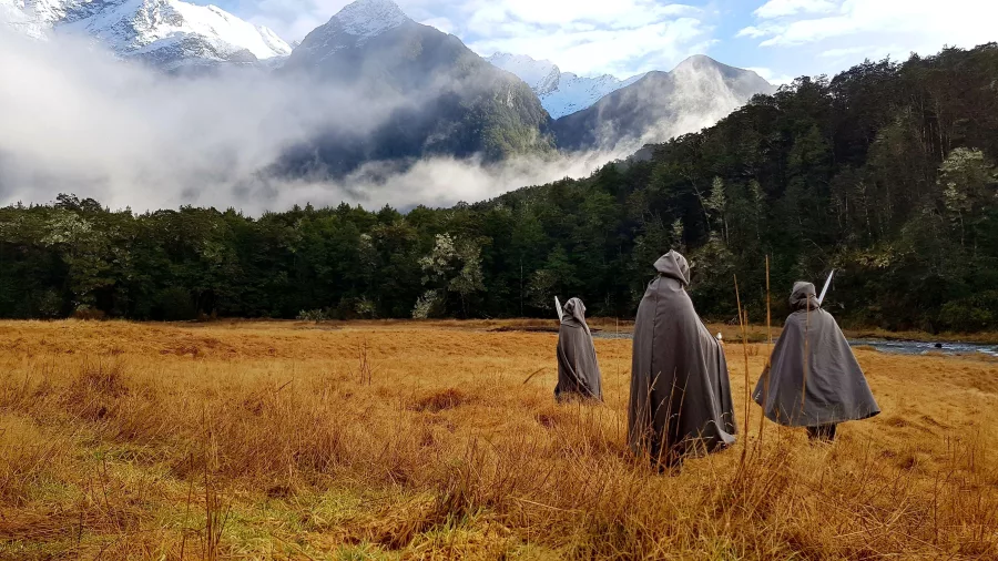Tour group dressed as characters from Lord of the Rings walking through a misty valley in New Zealand