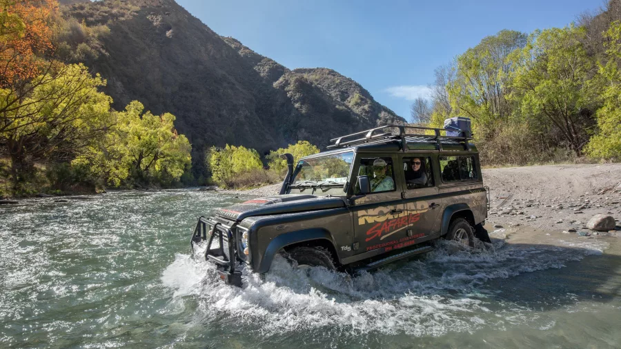 4WD Nomad Safaris vehicle driving through a shallow river near Queenstown