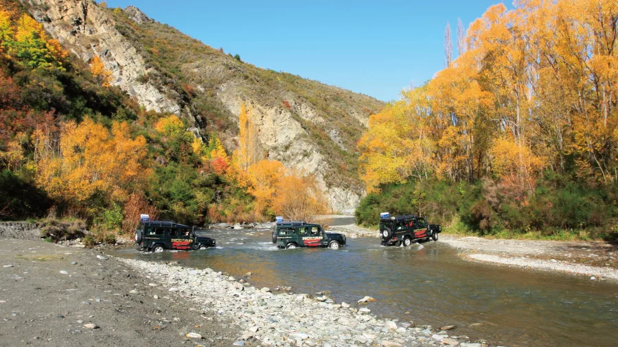 4WD convoy crossing the river in autumn during LOTR Queenstown tour