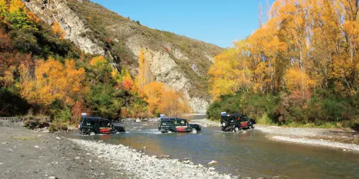 4WD convoy crossing the river in autumn during LOTR Queenstown tour