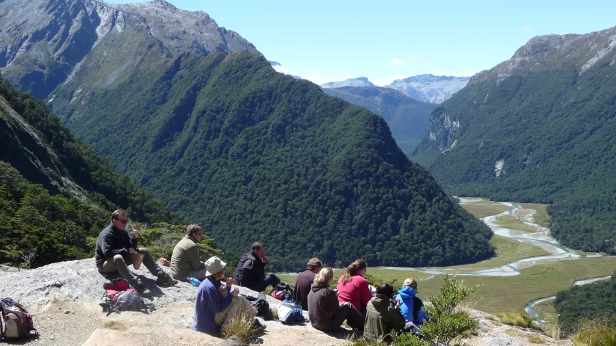 Group of hikers taking a break overlooking valley on Routeburn guided walk