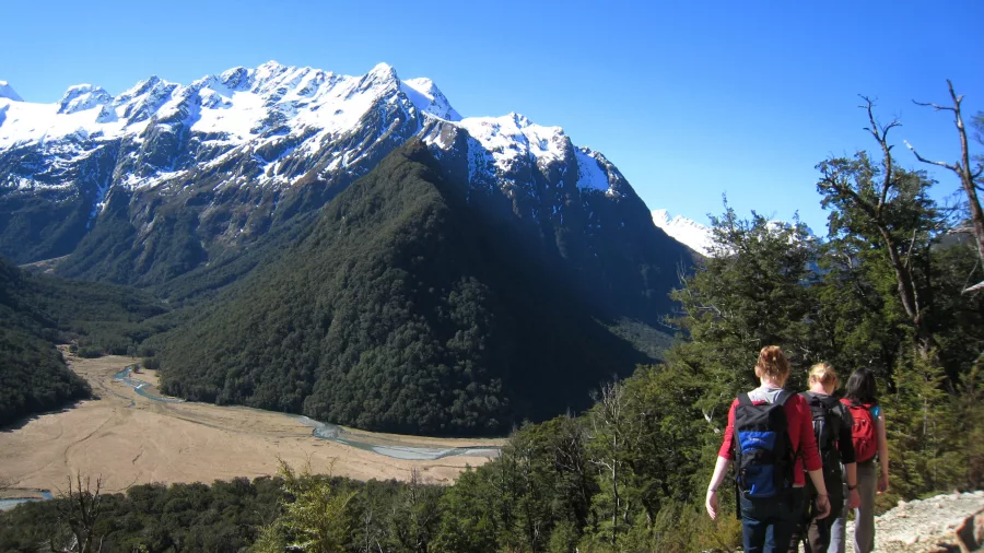 Walkers on Routeburn Track with snow-covered peaks in the background