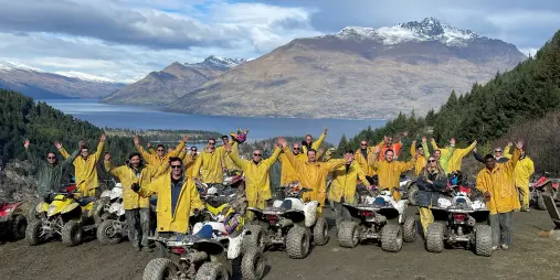 Quad biking group in yellow jackets celebrating on a scenic Queenstown trail
