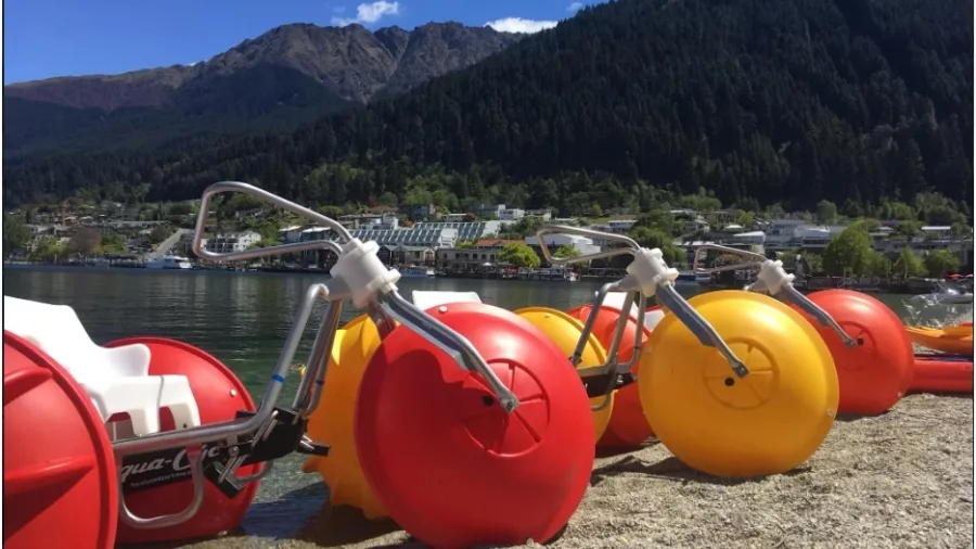 Aqua bikes parked on the lakeside shore near central Queenstown