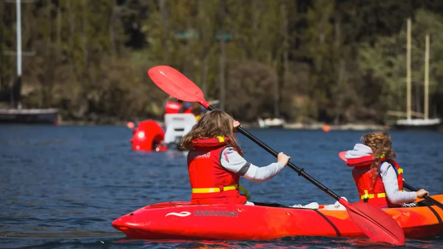 Two children kayaking together on Lake Whakatipu wearing life vests