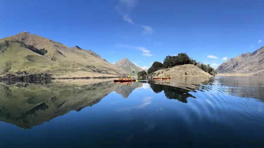 Group kayaking tour on Moke Lake with panoramic mountain reflections