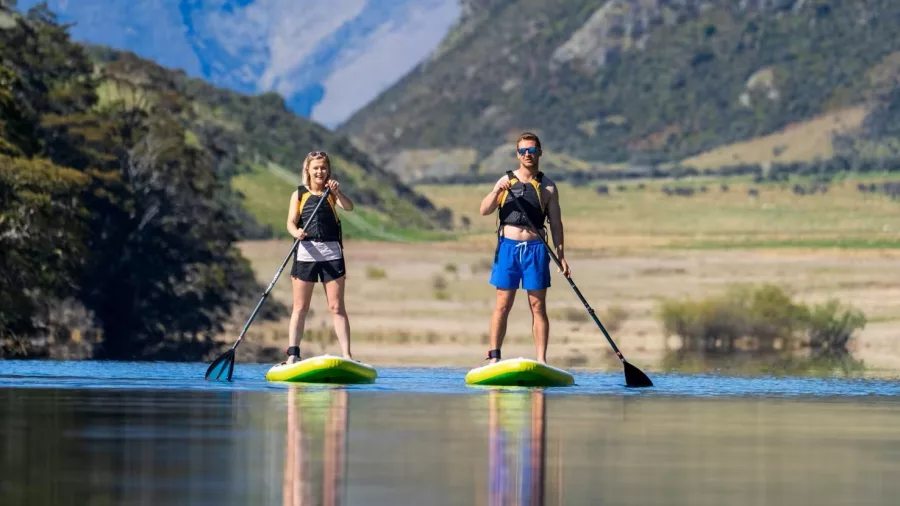 Couple paddleboarding on Moke Lake surrounded by mountains in Queenstown