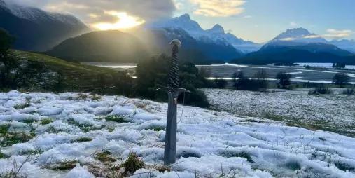 Sword planted in snow with dramatic mountains behind at a Lord of the Rings filming location