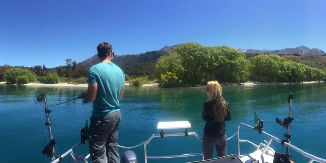 Man and woman fishing near the shore on a boat in Lake Wakatipu