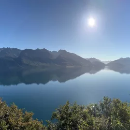 Wide panoramic view of Lake Wakatipu with glassy water and clear morning sun