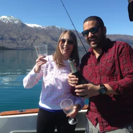Couple toasting with champagne on a fishing boat on Lake Wakatipu