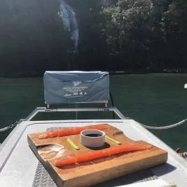 Fresh salmon sashimi served on a board with chopsticks on a fishing boat