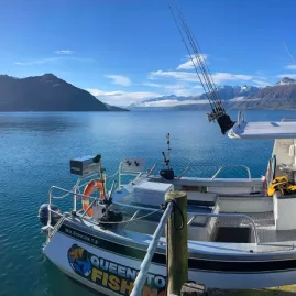 Fishing charter boat docked on Lake Wakatipu in Queenstown with mountains in background