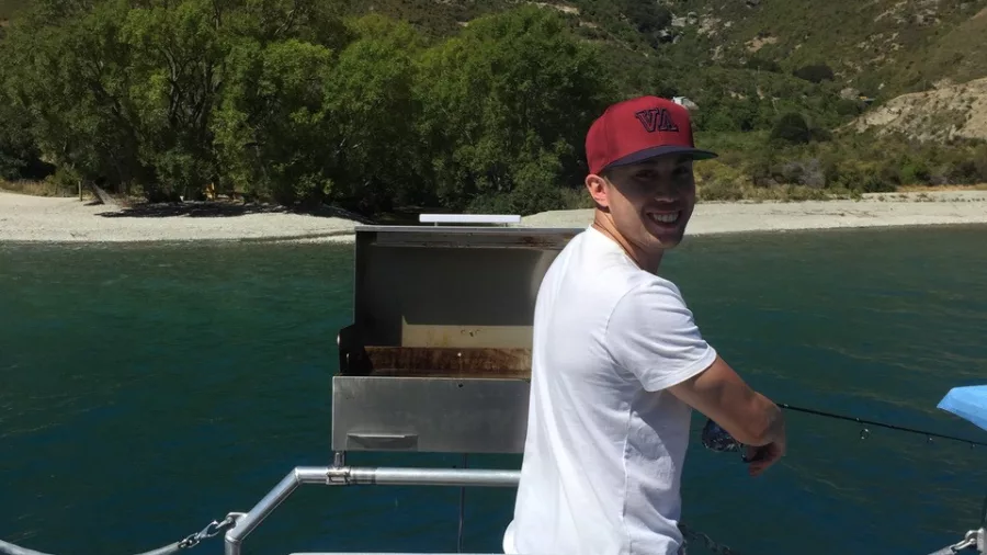 Man preparing cooked trout on a barbecue during a fishing trip on Lake Wakatipu