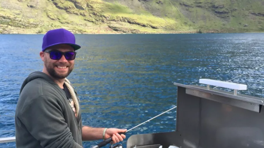 Man barbecuing freshly caught fish on a boat on Lake Wakatipu, Queenstown