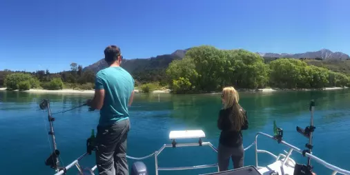 Man and woman fishing near the shore on a boat in Lake Wakatipu
