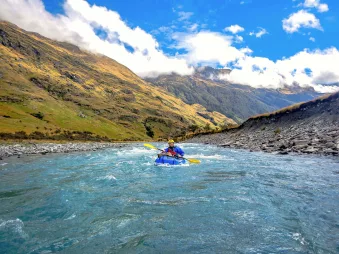 Packrafter paddling down a glacial river in Mount Aspiring National Park near Wanaka