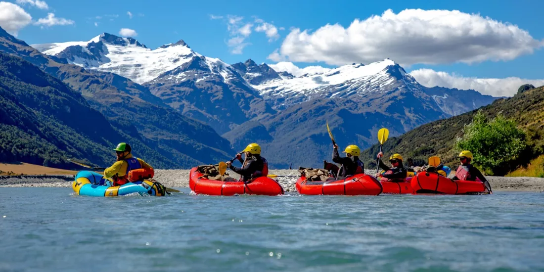 Group packrafting through Rees Valley beneath snow-capped peaks in Mount Aspiring National Park