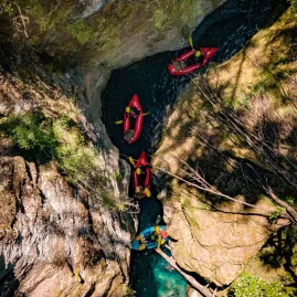 Aerial perspective of packrafters floating through a canyon in Rees Valley