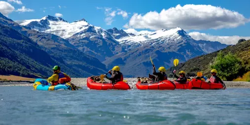 Group packrafting through Rees Valley beneath snow-capped peaks in Mount Aspiring National Park