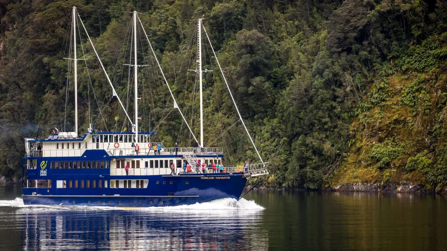 Fiordland Navigator cruise ship in Doubtful Sound surrounded by rainforest-covered cliffs