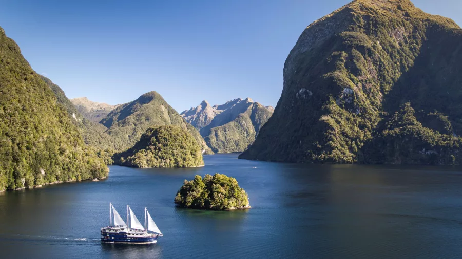 Aerial view of the Fiordland Navigator cruising through Doubtful Sound’s dramatic scenery