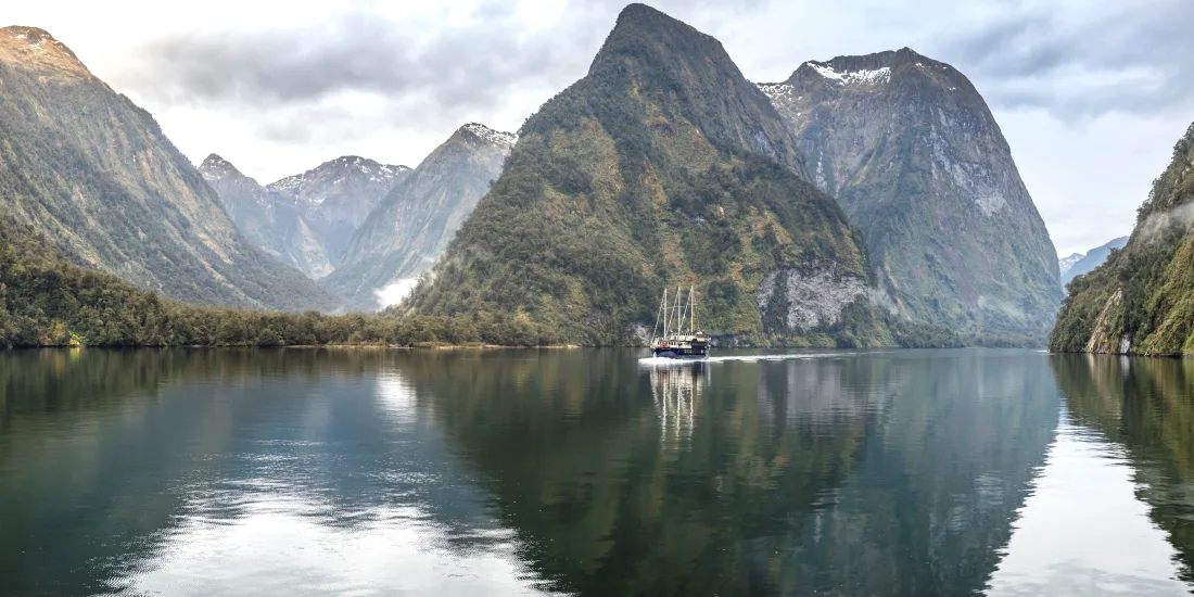 Fiordland Navigator cruising beneath the mountains of Doubtful Sound in New Zealand
