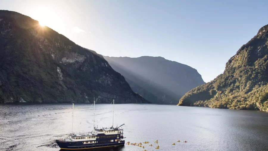 Fiordland Navigator with a large group of kayakers in Doubtful Sound at sunset
