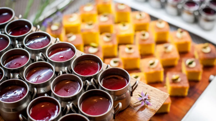 Colourful mini desserts in pots with passionfruit slices on wooden platters