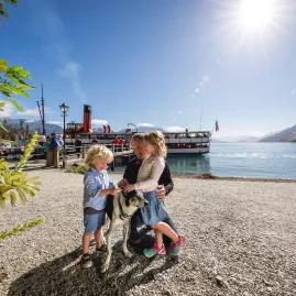 Children petting a dog with the TSS Earnslaw docked behind at Walter Peak