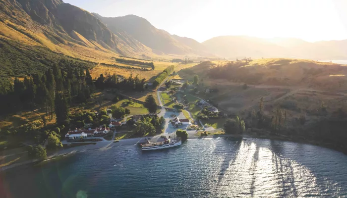 Aerial view of TSS Earnslaw arriving at Walter Peak Station in golden light