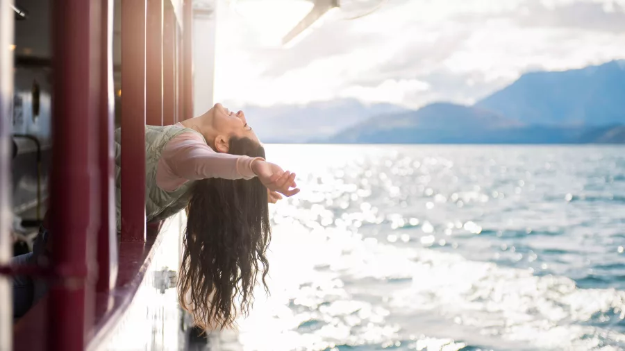 Woman leaning out from the TSS Earnslaw, soaking up sunshine and lake views