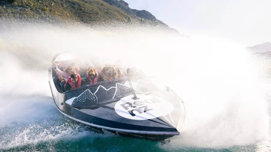 Jet boat racing across Kawarau River creating a massive water spray