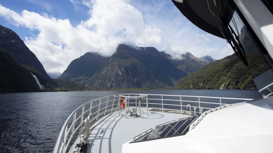 View from the deck of a luxury cruise through Milford Sound, surrounded by Fiordland’s dramatic peaks