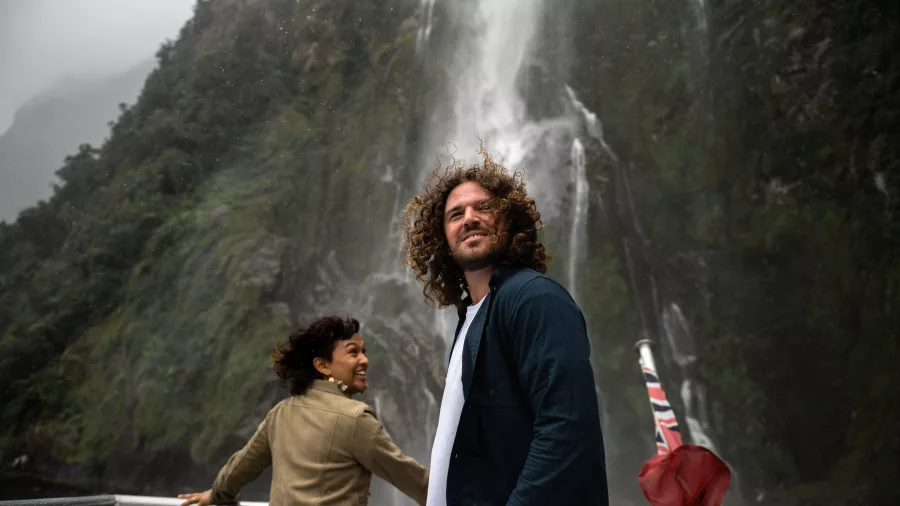 Couple standing on deck admiring Stirling Falls in Milford Sound