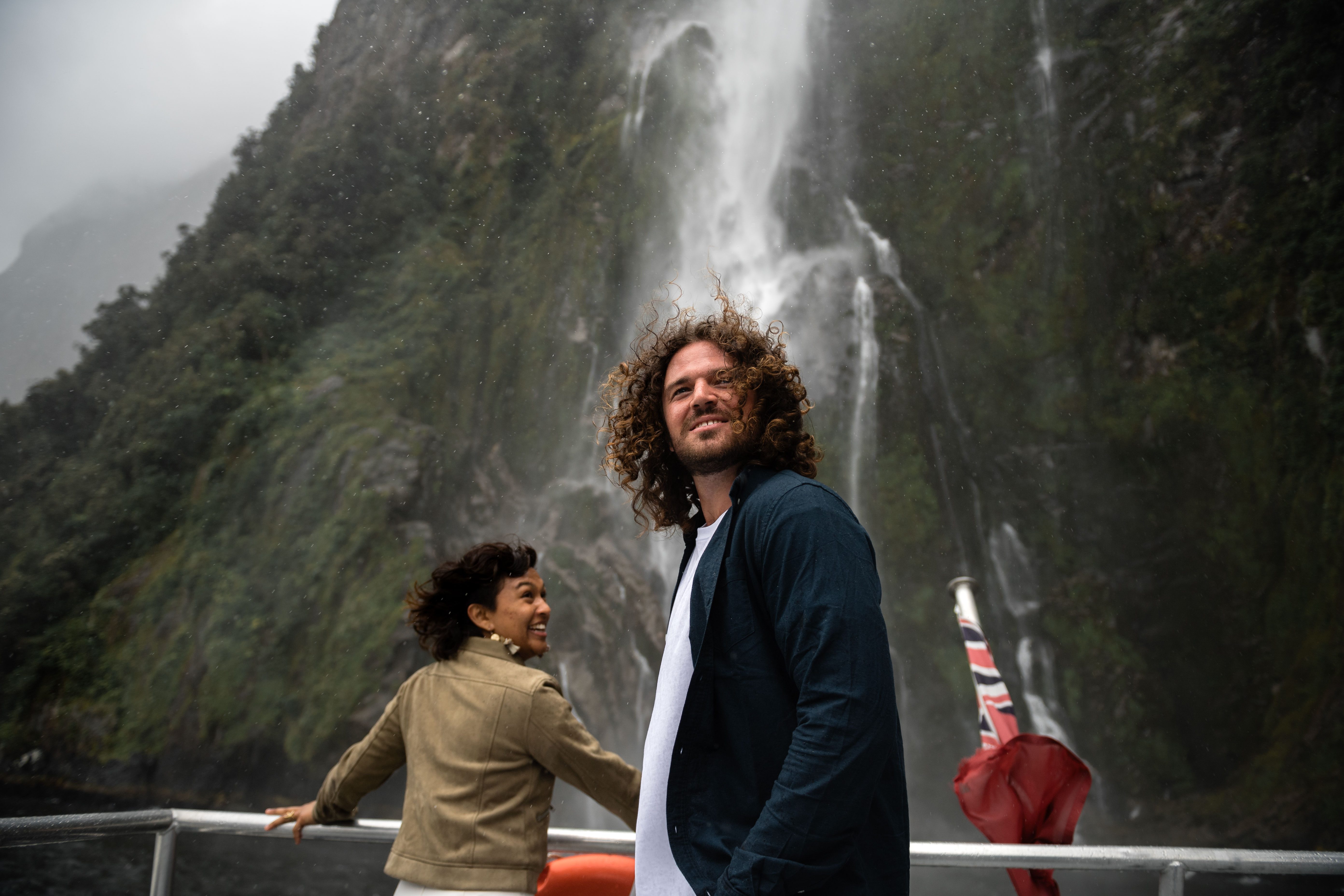 Couple standing on deck admiring Stirling Falls in Milford Sound