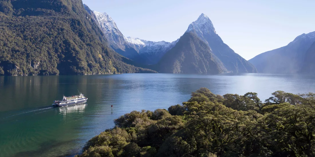 The Milford Haven cruise boat gliding through Milford Sound near forested shorelines and snowy peaks