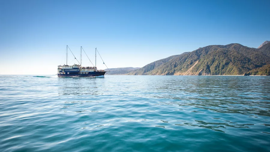 Milford Mariner cruising in open water with Fiordland coastline in the distance