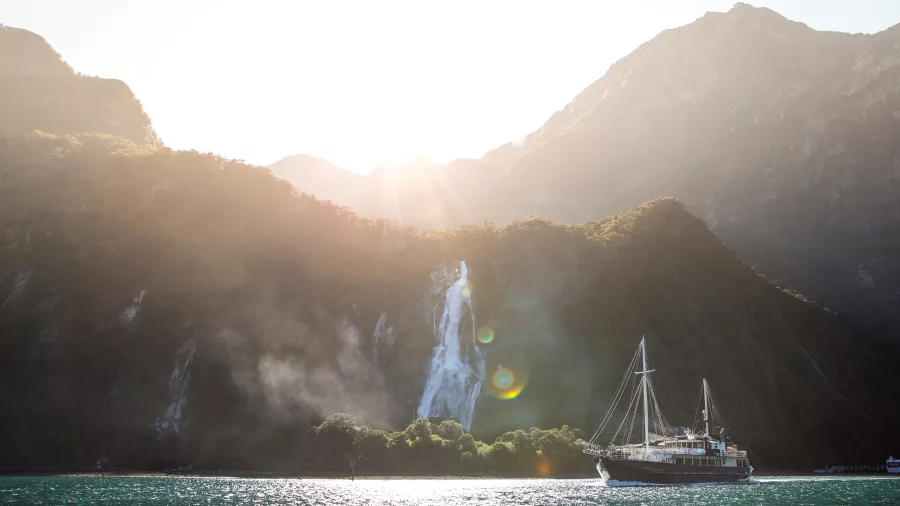 Milford Wanderer cruising past Bowen Falls at sunset in Milford Sound