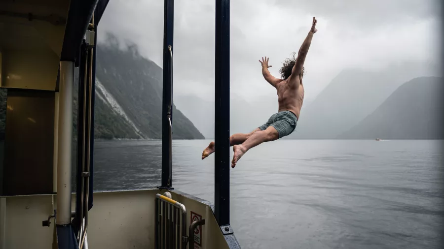 Guest leaping into the water from the Milford Mariner during an overnight cruise in Milford Sound