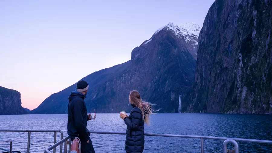 Couple enjoying sunrise views of Milford Sound from the deck of Milford Mariner