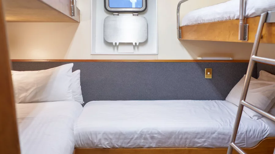Quad-share bunk cabin with porthole window onboard the Milford Mariner