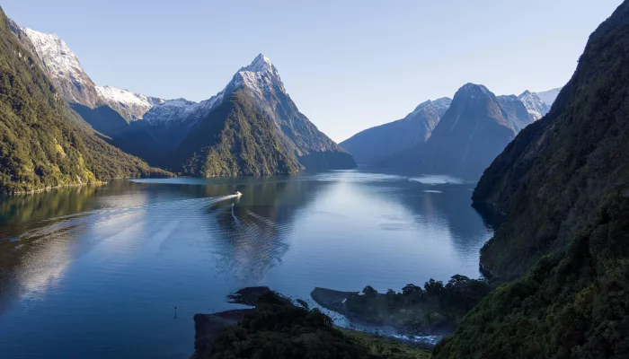 Aerial view of a boat cruising through Milford Haven surrounded by towering cliffs